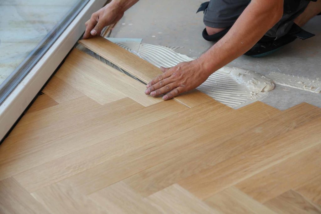 Worker laying parquet flooring. Worker installing wooden laminate flooring.