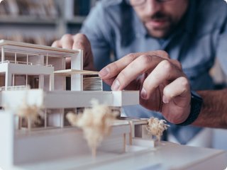 An architect's workspace featuring a detailed architectural 3D building on a drafting table