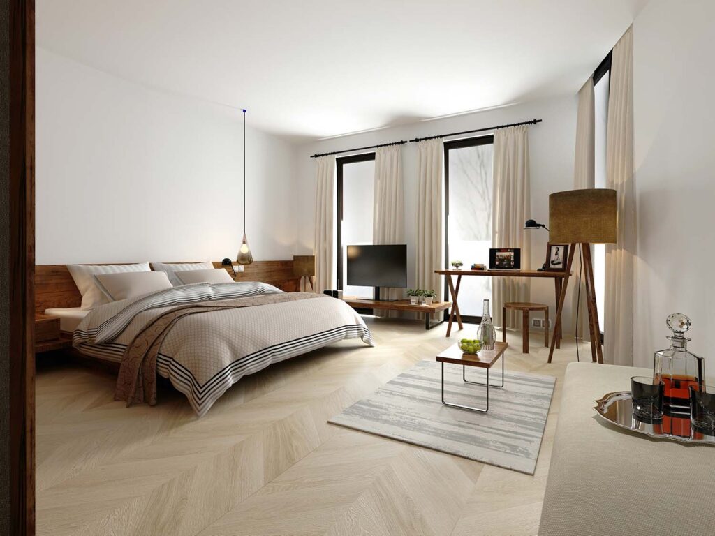 Photo of a stylish bedroom featuring a beautiful chevron-patterned wooden floor. The flooring showcases alternating light and dark wood tones arranged in a V-shaped pattern, adding a dynamic and elegant touch to the room